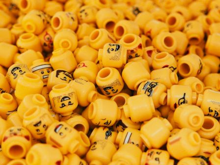 The image shows a large pile of yellow Lego minifigure heads, each with various facial expressions.